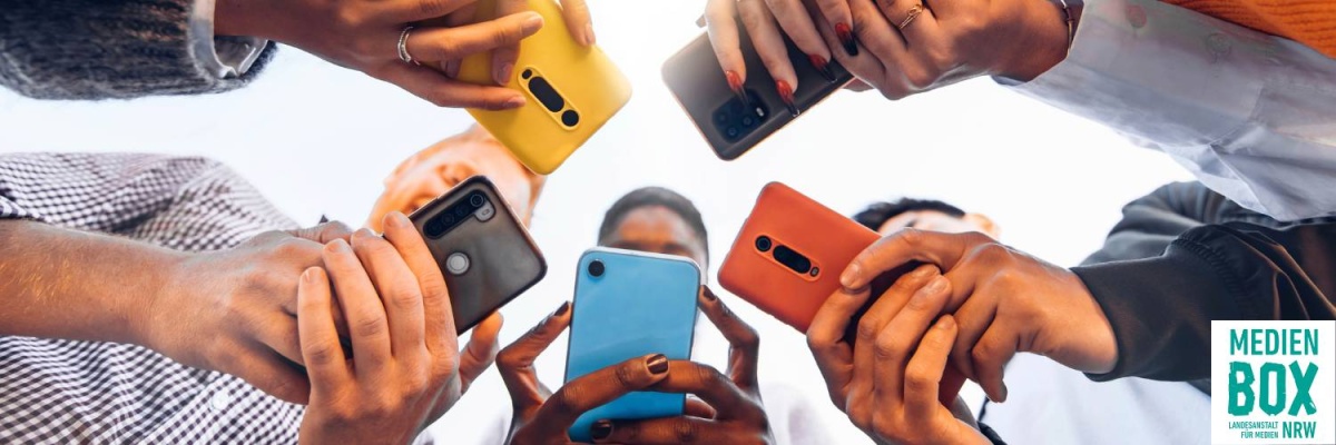 Menschen stehen im Kreis und schauen auf ihre Mobiltelefone