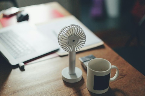 Büro mit einer Kaffeetasse und einem kleinen Ventilator