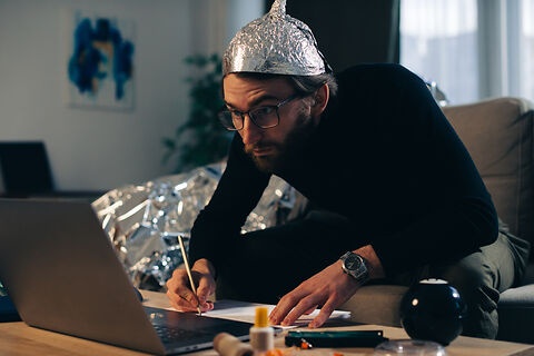 Mann mit Aluhut vor seinem Computer